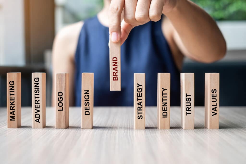 Businesswoman hand placing or pulling wooden Dominoes with BRAND – IT STIX
